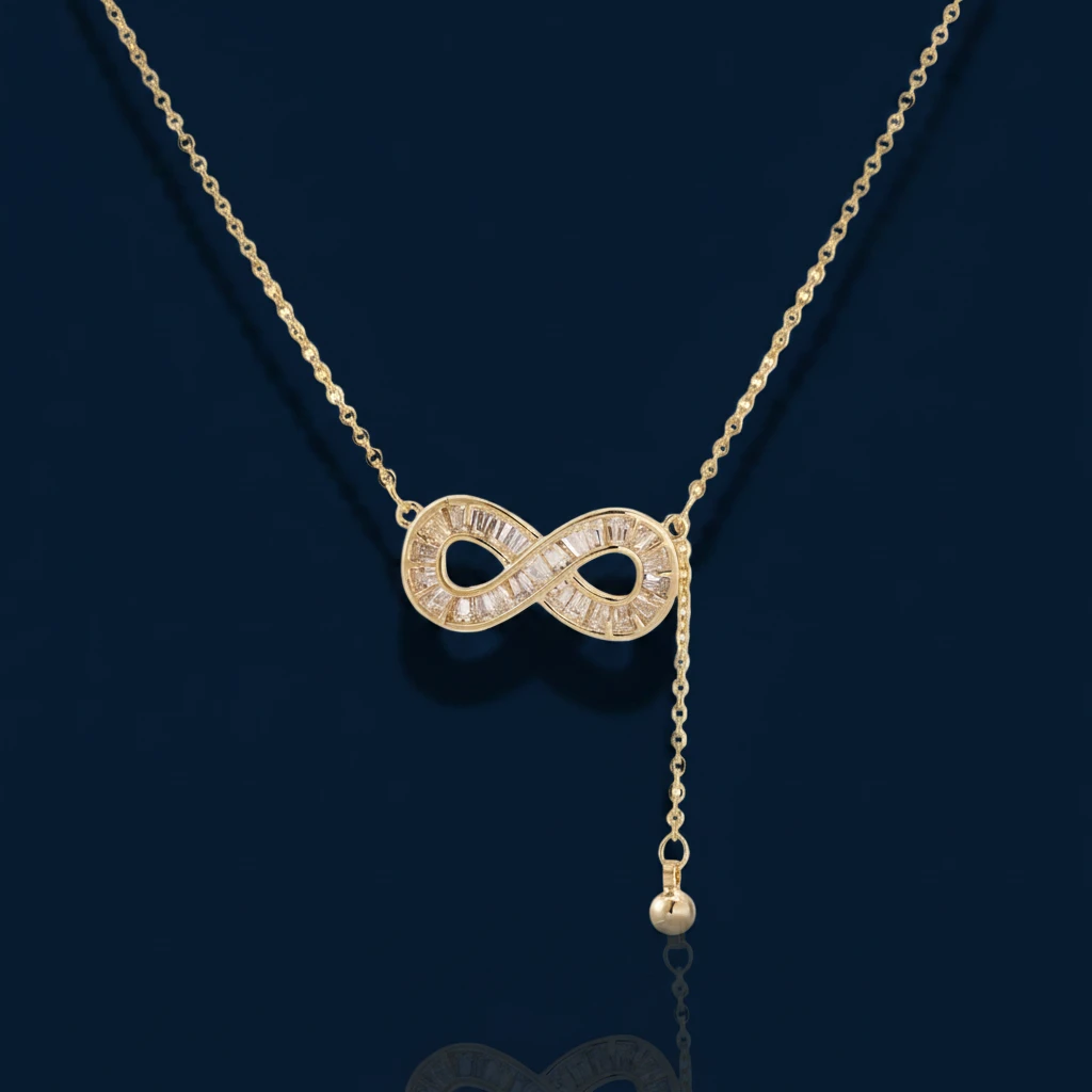Gold infinity pendant with baguette crystals on adjustable chain against cream background.